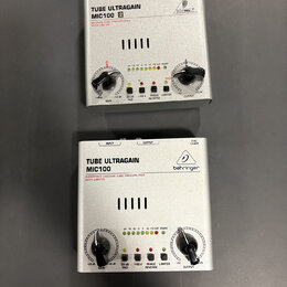 Dvě stříbrná zařízení s nápisem TUBE ULTRAGAIN MIC100. Horní jednotka má vedle modelu bílé čtverečky s čísly 1 a 2 a logo BEHRINGER v kruhu. Spodní j…