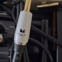 Fotografie zachycuje konektor typu jack v zlatém provedení s bílým plastovým krytem. Na krytu je černé logo ve tvaru písmene M a nápis MONSTER CABLE.…