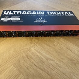 Černý rackový audio interface s červeným horním panelem. Na spodní straně je nápis ULTRAGAIN DIGITAL AUDIOPHILE 8 IN/8 OUT ADAT AUDIO INTERFACE MODEL…