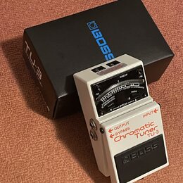 Bílý kytarový ladič s černým spátkem a ovládacími prvky. Na zařízení je uveden nápis BOSS, Chromatic Tuner TU-3 a OUTPUT BYPASS INPUT. Vedle ladiče j…