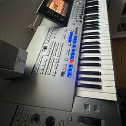 Šedý digitální klavír s bílými a černými klávesami. Nástroj disponuje dotykovým displejem, řadou tlačítek a dvěma posuvníky v dolní části. Na levém p…