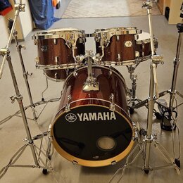 Tmavě červená bicí souprava s kovovým kováním. Na přední straně basového bubnu je bílé logo a nápis YAMAHA. Souprava obsahuje basový buben, dva tom-t…
