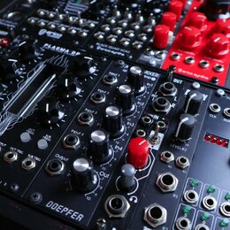 Fotografie zachycuje několik modulů Eurorack syntetizátoru v černém racku. V popředí je modul s nápisy PLASMA DP, MIXER a DOEPFER, vybavený několika…