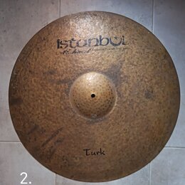 Kruhová mosazná činely s kladeným povrchem. V horní části je černý nápis „istanbul“ a pod ním menší text „Mehmet Handmade cymbals from Turkey“. Ve sp…