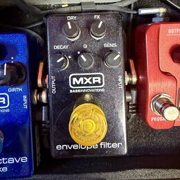 Černý efekt pedál s nápisy MXR, BASSINNOVATIONS a envelope filter. Na horní části jsou čtyři ovládací knoflíky s popisky DRY, FX, DECAY a SENS, upros…