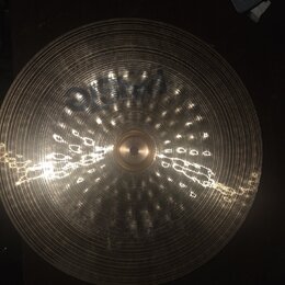 Kruhový mosazný činel s koncentrickými drážkami na povrchu. Na horní části je viditelný tmavý nápis PAISTE. Povrch vykazuje odrazy světla a drobné ne…