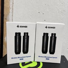 Dvě bílé krabice s nápisem DONNER a označením Wireless Microphone System CV-2. Na krabicích jsou vyobrazeny dva černé bezdrátové mikrofony. Krabice s…