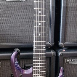 Fialová elektrická kytara s tmavým hmatníkem a dvěma humbuckery. Na hlavě je svisle napsáno "Mayones" a nahoře je podpis. Spodní část korpusu obsahuj…