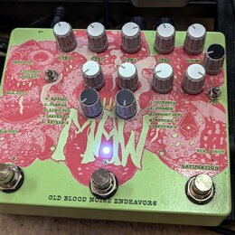 Světle zelený efekt pedál s červeným grafickým motivem. Na spodní hraně je nápis OLD BLOOD NOISE ENDEAVORS. Zařízení má deset bílých a dva černé ovlá…