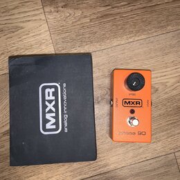 Oranžový kytarový efekt s černým ovládacím knoflíkem a nápisy SPEED, OUTPUT, INPUT a MXR. Ve spodní části je vyražen text phase 90. Vedle efektu leží…