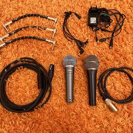 Sada vybavení složená ze dvou dynamických mikrofonů, kabelů a napájecího adaptéru. Na mikrofonech jsou viditelné nápisy "Sennheiser" a "Cobalt 810".…