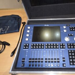 Modrý digitální mixovací pult Magic O M050 v hliníkovém přepravním kufru. Zařízení má centrální displej, několik otočných knoflíků a velké množství č…