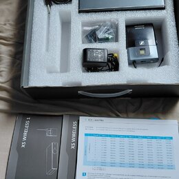 Sada bezdrátového systému v originální krabici s pěnovou výplní. Obsahuje šedý přijímač, černý vysílač s logem SENNHEISER a nápisem XS WIRELESS, napá…
