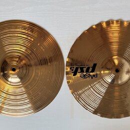 Dva mosazné činely s koncentrickým žebrováním. Na obou je černé logo Paiste a nápis ps5. Levý činel má nápis 14" SQUARED EDGE HI-HATS TOP a pravý náp…