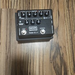 Černý efekt pedál s nápisy MXR, BASS INNOVATIONS a bass d.i.+. Na horní straně jsou čtyři otočné ovladače s popisky DISTORTION, GATE, COLOR a nečitel…