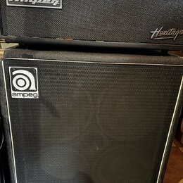 Černý basový zesilovač a reproduktorová skříň. Na horním přístroji je nápis Heritage SVT-CL, logo Ampeg a nápis Heritage. Spodní skříň má v horní čás…