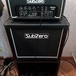 Černý kytarový kombozesilovač značky SubZero složený z hlavy a boxu. Na předním panelu hlavy je nápis SubZero a označení modelu SA20E. Na mřížce spod…