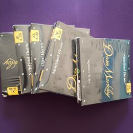 Šest balení kytarových strun v šedých obalcích s modrým přechodem. Na obalech jsou nápisy „NickelSteel Electric™“, „Dean Markley“ a „Signature Series…