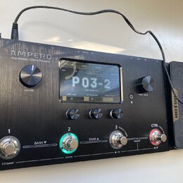 Černý efektový procesor s nápisem AMPERO Amp Modeler / Effects Processor. Zařízení má digitální displej, na kterém je zobrazen text P03-2 a další par…