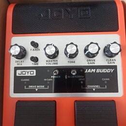 Oranžový kytarový kombo zesilovač s černým reproduktorem. Na ovládacím panelu jsou knoflíky s popisky DELAY MIX, F.BACK, TIME, MASTER VOLUME, TONE, D…