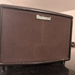 Černý kompaktní kytarový kombo zesilovač s hnědou texturovanou síťovkou. V horní části je umístěno bílé logo Roland. Na hranách šasi jsou viditelné d…