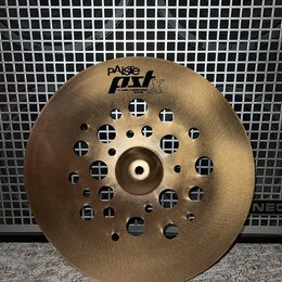 Zlatavý kovový činel s několika průřezem v podobě otvorů různých velikostí. Na povrchu je černý nápis pAiste PST X a pod ním menší text 14" BRASS FLA…