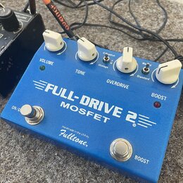 Modrý kytarový efekt s nápisy VOLUME, TONE, OVERDRIVE a BOOST. Na horní straně je velký bílý nápis FULL-DRIVE 2 MOSFET a pod ním text Handmade in the…