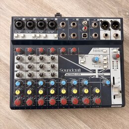 Černý mixážní pult s bílými a šedými popisky. Na předním panelu je vidět značka Soundcraft a název modelu NOTEPAD-12FX, dále nápis Lexicon EFFECTS a…