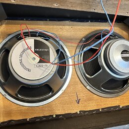 Dva reproduktory montované v dřevěné bedně s viditelným zapojením červených a modrých vodičů. Levý reproduktor má na magnetu nápisy PROFESSIONAL LOUD…