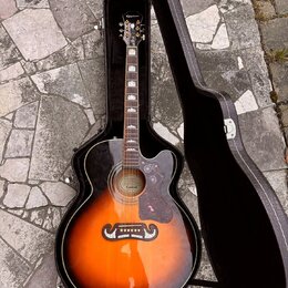 Akustická kytara s korpusem v barvě sunburst, umístěná v černém tvrdém pouzdře. Na hlavě hředu je bílý nápis Epiphone a na úzkém pásku v místě mostu…