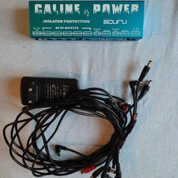 Zelený napájecí adaptér pro pedály s nápisy GALINE P1 POWER a ISOLATED PROTECTION. Na pravé straně je logo souru a pod ním řada výstupů s označením D…