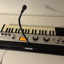 Černý syntetizátor s klaviaturou a ovládacím panelem. Na pravé straně je nápis KORG microKORG XL a na spodní hraně uprostřed logo KORG. Přístroj má v…