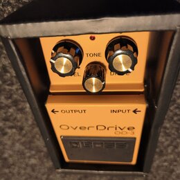Oranžový kytarový efekt v černé krabici. Na horní části je nápis OverDrive, OD-3 a označení INPUT a OUTPUT se šipkami; v horní části je černé pole s…