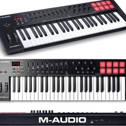 Černý MIDI kontrolér s klaviaturní klávesí, červenými podsvícenými pady a ovládacími prvky v horní části. Na přístroji jsou viditelné nápisy M-AUDIO…