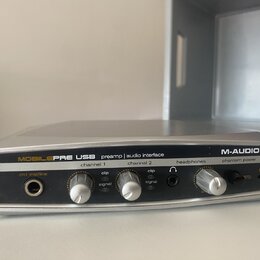 Stříbrné audio rozhraní s nápisy MOBILEPRE USB preamp | audio interface a M-AUDIO. Zařízení má dva regulační knofíky pro channel 1 a channel 2, každý…