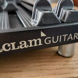 Detailní záběr na černý kovový most hudebního nástroje. Na boku je bílý nápis „aclam GUITARS“ s malým trojúhelníkem nad písmenem M a symbolem ® v pra…