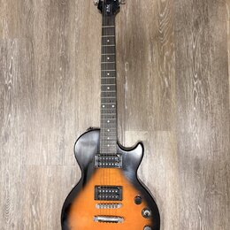 Elektrická kytara s tónem sunburst v oranžovo-černé kombinaci a tmavým hmatníkem. Na hlavě je bílý nápis Epiphone a pod ním stylizovaný nápis Les Pau…