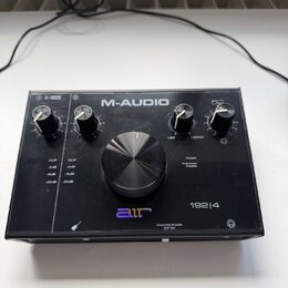 Černý audio rozhraní s nápisem M-AUDIO a označením modelu 192|4. Na předním panelu je velký centrální ovládací knoflík, čtyři menší knoflíky a logo a…