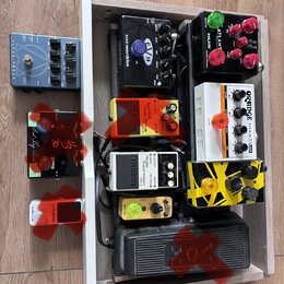 Sestava kytarových efektů v dřevěném rámu. Jsou zde pedály s nápisy ALPHA ONES, EVH 5150 overdrive, NUX ATLANTIS, ORANGE STAGE STAMP a BOSS NS-2 Nois…