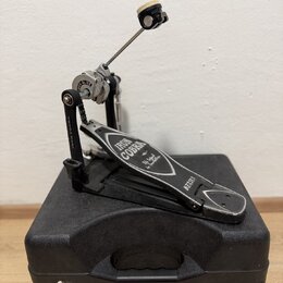 Černý basový pedál s kovovými prvky, umístěný na černém tvrdém kufru. Na pedálu je bílý nápis IRON COBRA a dále menší text, který je nečitelný, a náp…