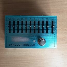 Modrý ekvalizér s kovovým povrchem a nápisem BAND CONTROLLER. Zařízení obsahuje 10 posuvníků s označením frekvencí od 31.25 Hz do 16K Hz a jeden posu…
