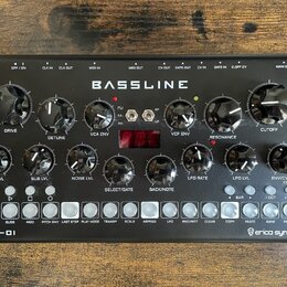Černý syntezátor s nápisem BASSLINE a DB-01 v levém dolním rohu. V pravém dolním rohu je logo erica synths. Přístroj obsahuje několik černých otočnýc…