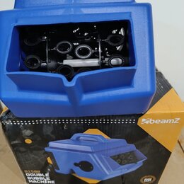 Modrá plastová bublinová stavební jednotka s viditelným vnitřním mechanismem černých ozubených kol a bílého válce. Zařízení stojí na své originální k…