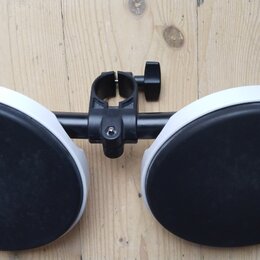 Dva kulaté černý padové bubny s bílým okrajem, které jsou upevněny na černé kovové hromádce. Celý mechanismus je umístěn na světlém dřevěném povrchu.…
