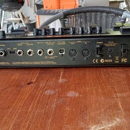 Zadní strana kytarového procesoru v černé barvě. Na přístroji je vidět logo BOSS a model GT-100, dále nápisy MODEL GT-100 a SER. No. E7E3084, spolu s…