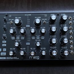 Černý semi-modulární analogový syntetizátor s dřevěnými bočními panely. Na spodní liště je bílý nápis SUBHARMONICON SEMI-MODULAR ANALOG POLYRHYTHMIC…