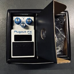 Bílý efekt pedál s černým spodním panelem umístěný v originální černé krabici. Na zařízení je nápis Plugout FX PX-1 a logo BOSS. Horní část obsahuje…