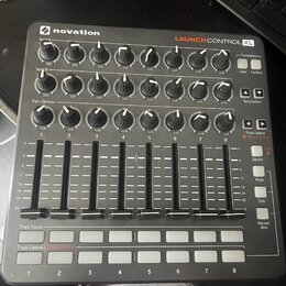 Černý MIDI kontrolér značky novation s nápisem LAUNCH CONTROL XL. Zařízení obsahuje tři řady otočných knoflíků s bílými indikátory, osm posuvníků a d…