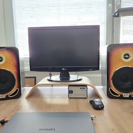 Dva studiové monitory s dřevěným provedením v přechodové barvě od žluté po tmavě hnědou. Na spodní části každého reproduktoru je viditelné logo Gibso…