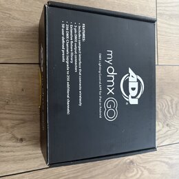 Černá papírová krabice s bílým textem a logem. Na povrchu je uveden název my dmx GO, popis DMX Lighting Control APP for iPad or Android a logo ADJ. V…